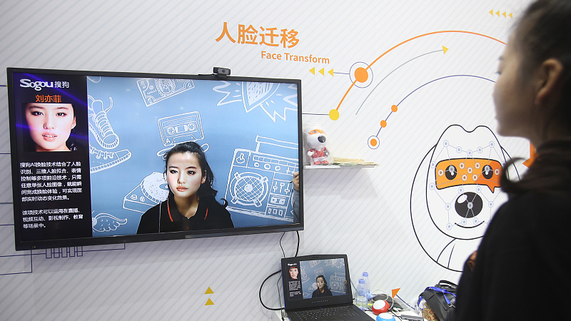 A woman stands in front of an AI application which can change her face to a targeted celebrity face via the camera at an expo in Shenzhen, November 14, 2018. /CFP