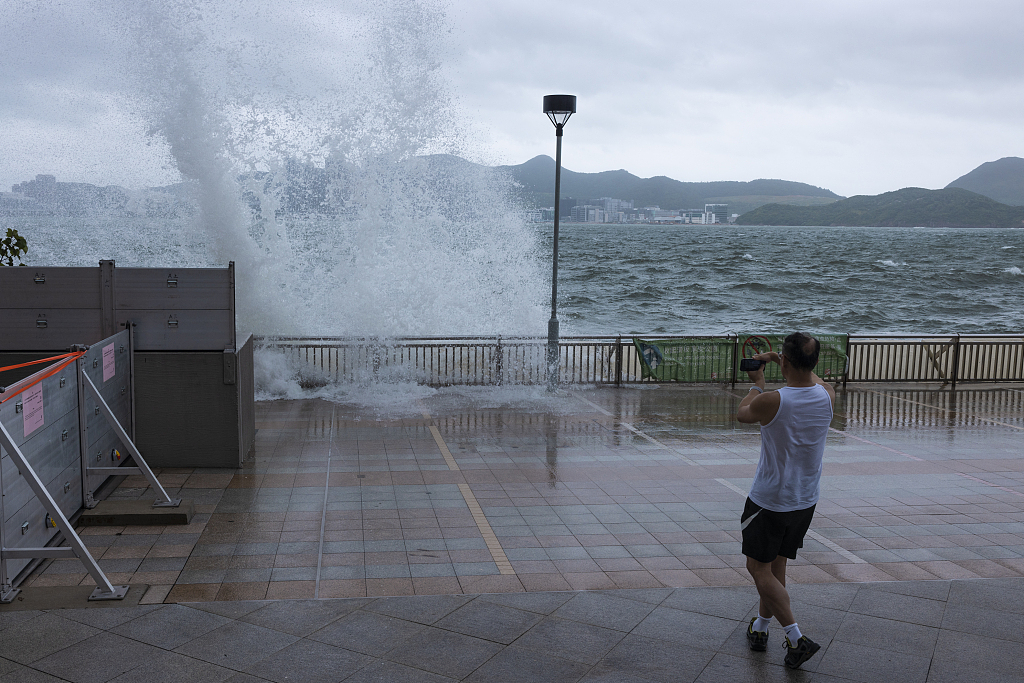 A man looks at the waves on a promenade during a typhoon in Hong Kong, China, July 17, 2023. /CFP