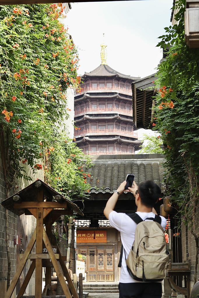 2023年6月18日，一名年轻人在长沙铜官窑古镇的一座历史建筑前拍照。/CFP