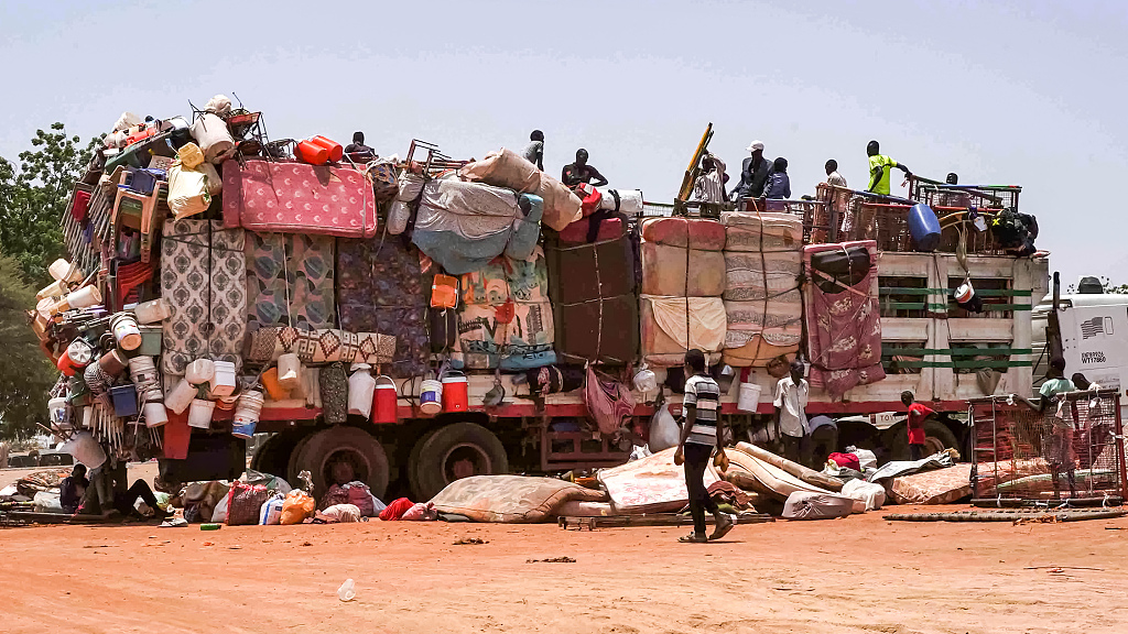 People sit atop a truck carrying mattresses, plastic chairs and other pieces of furniture parked along the road in Al-Hasahisa, Sudan, July 18, 2023. /CFP