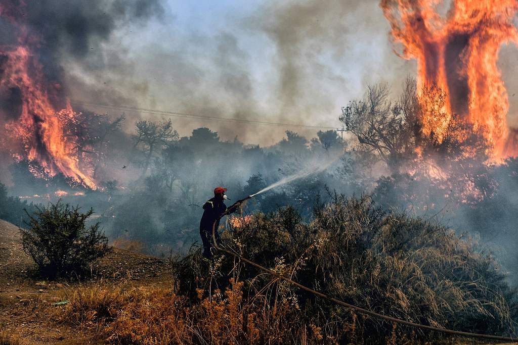 A fireman douses the flames of a wildfire at the Panorama settlement near Agioi Theodori, some 70 kilometers west of Athens, July 18, 2023. /CFP