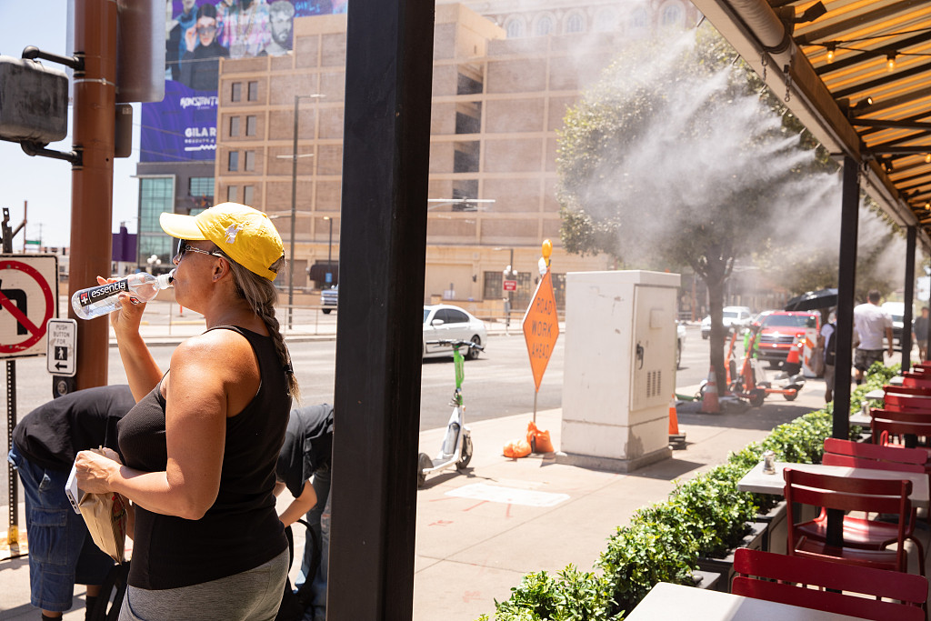 A resident drinks water while standing next to misters during a heat wave in Phoenix, Arizona, the U.S., July 20, 2023. /CFP
