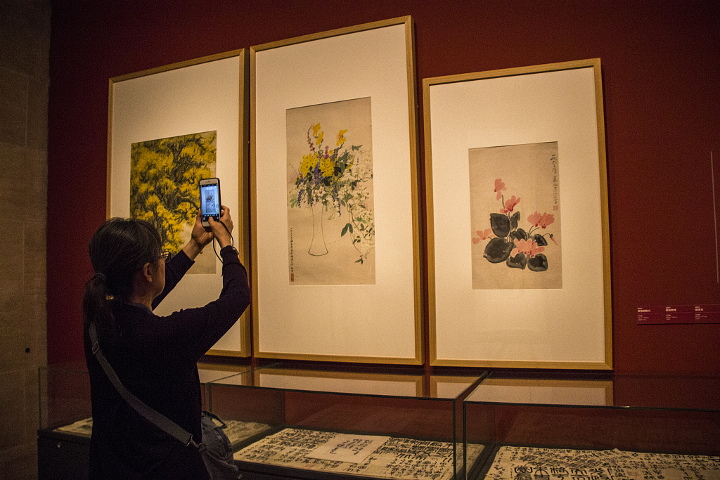 This photo taken on September 22, 2018, shows a visitor viewing artworks by Wu Zuoren and Xiao Shufang on display at the National Art Museum of China. /CFP