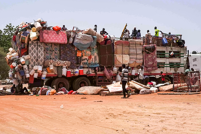 People sit atop a truck carrying mattresses, plastic chairs and other pieces of furniture parked along the road near Sudan's capital Khartoum, July 18, 2023. /CFP