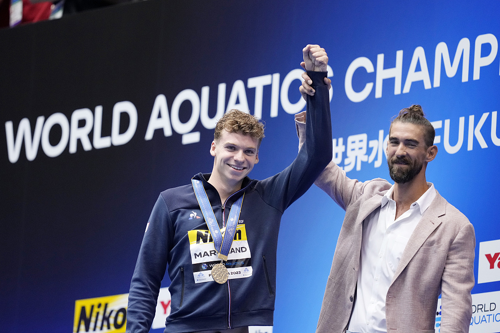 Michael Phelps (R) and gold medalist Leon Marchand celebrate during men's 400 meter individual medley award ceremony at the World Aquatics Championships in Fukuoka, Japan, July 23, 2023. /CFP