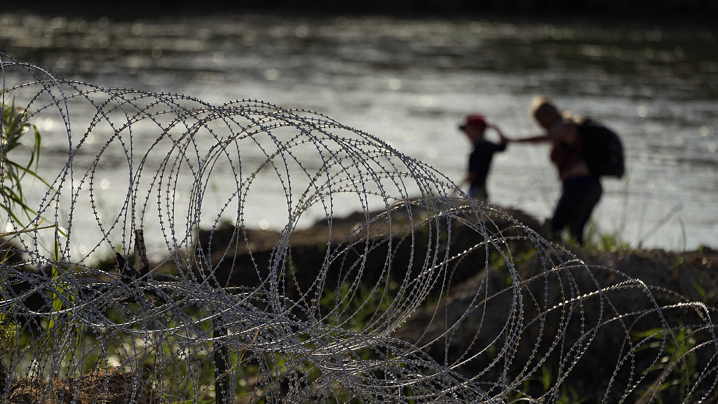 Migrants walk along concertina wire as they try to cross the Rio Grande at the Texas-U.S. border in Eagle Pass, Texas, U.S., July 6, 2023. /CFP
