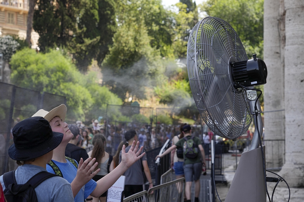 Tourists cool off near a fan as they queue to enter Rome's Colosseum, Italy, on July 18, 2023. /VCG