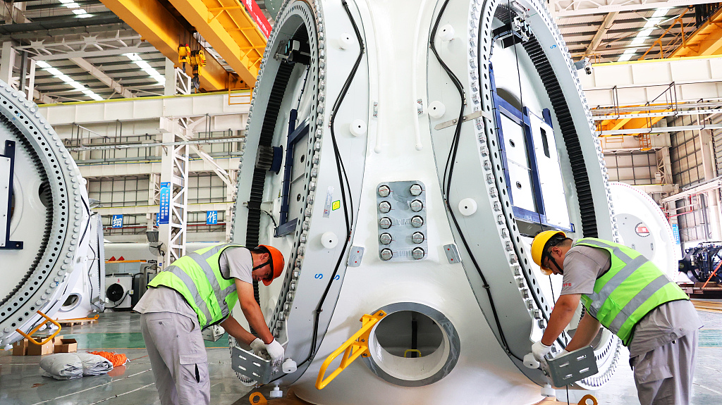 Workers assemble a wind turbine hub, in Lianyungang, Jiangsu Province, July 27. /CFP