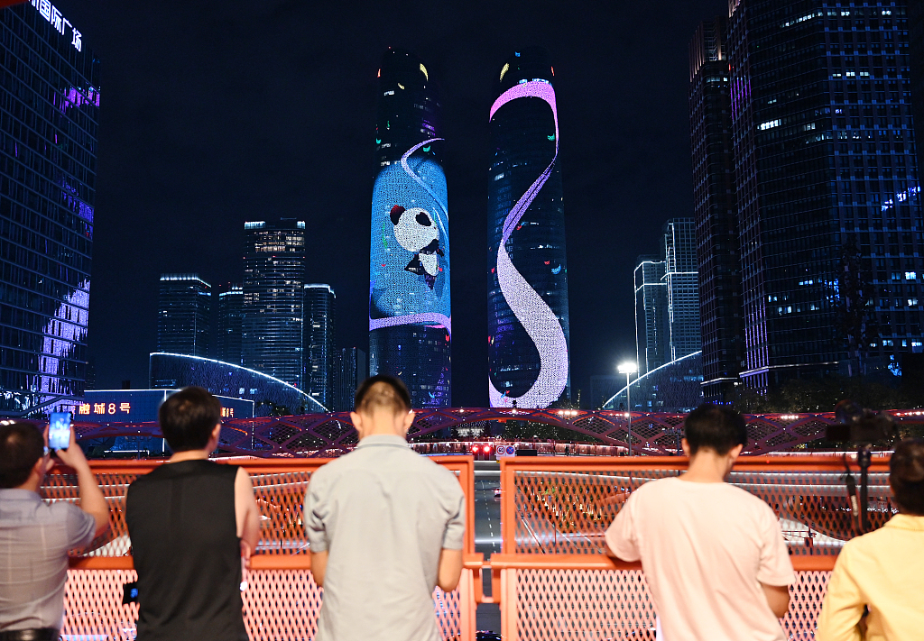 This photo, taken on July 28, 2023, shows residents taking photos of sports-themed images projected onto the Twin Towers in Chengdu, Sichuan Province. /CFP