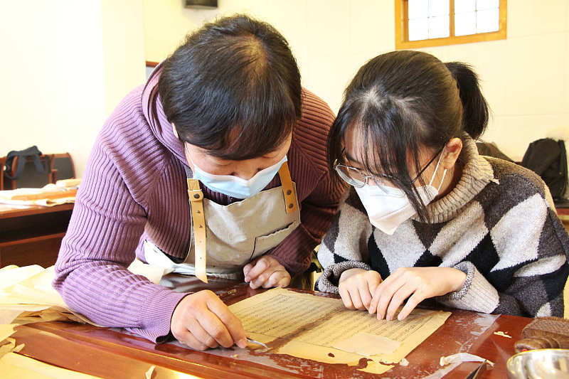 A teacher guides a student on how to restore ancient books at the Shandong Library in Jinan City, Shandong Province, February 1, 2023. /CFP