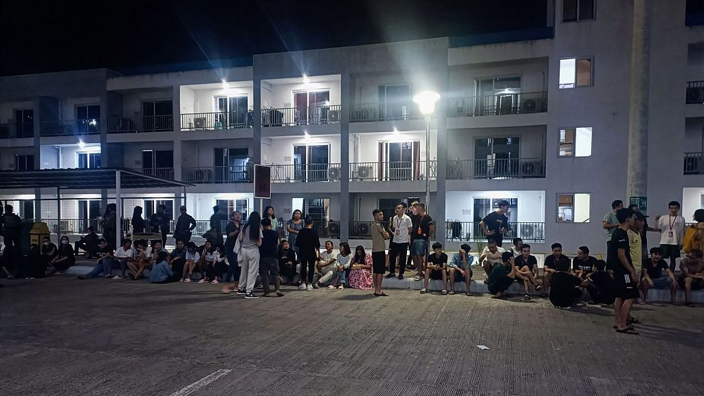 Rescued trafficked people standing outside a building after a police raid inside a freeport zone in Mabalacat City, in Pampanga province, north of Manila, May 4, 2023. /CFP