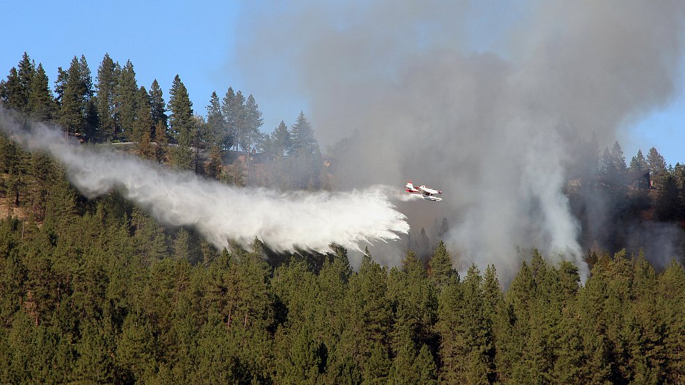 A plane dropping water on the forest fire. /CFP