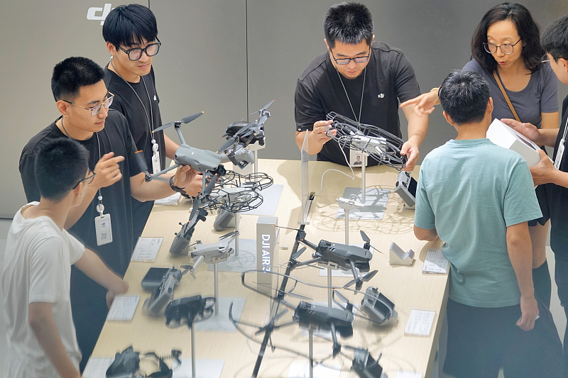 DJI salespersons talking about their products to customers in a store in east China's Shandong Province on July 30, 2023. /CFP