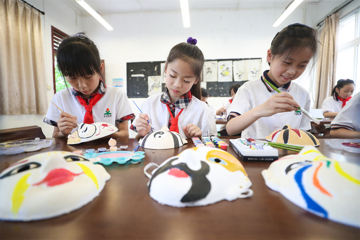 Students from a primary and middle school in Luoshe County, Huzhou City, east China's Zhejiang Province, paint Peking Opera face masks in class, June 8, 2023. /CNSPHOTO