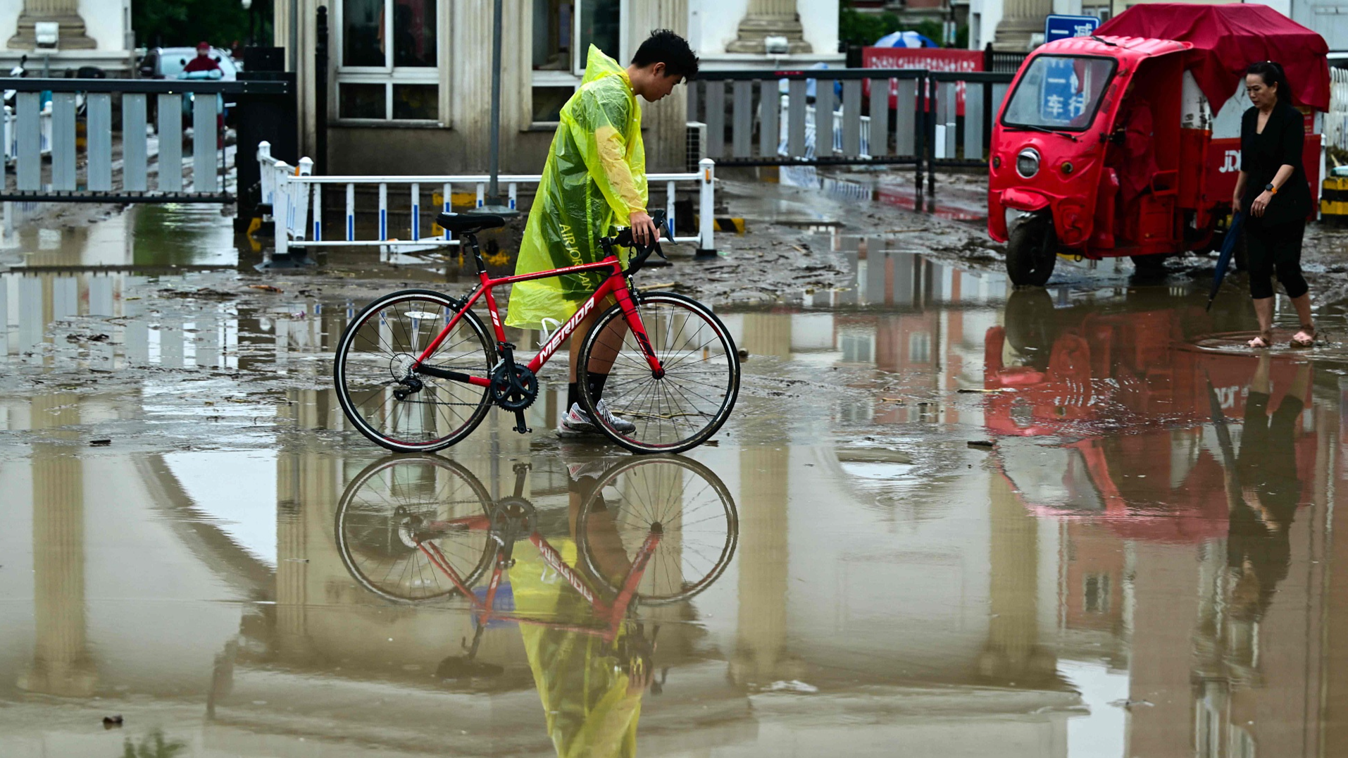 People walk along a water laden street after heavy rains in Mentougou District in Beijing on July 31, 2023. /CFP