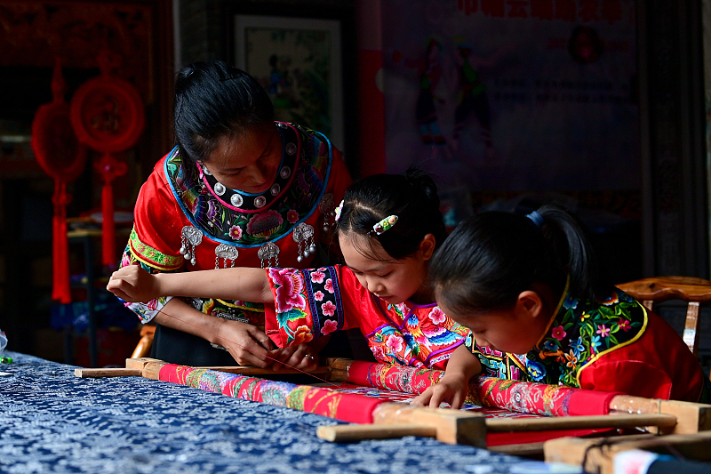 Children learn the traditional embroidery skills of the Miao ethnic group at Youzhou Ancient Town in Chongqing Municipality. /CFP