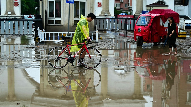 People walk along a water laden street, after heavy rains in Mentougou district in Beijing, China, July 31, 2023. /CFP