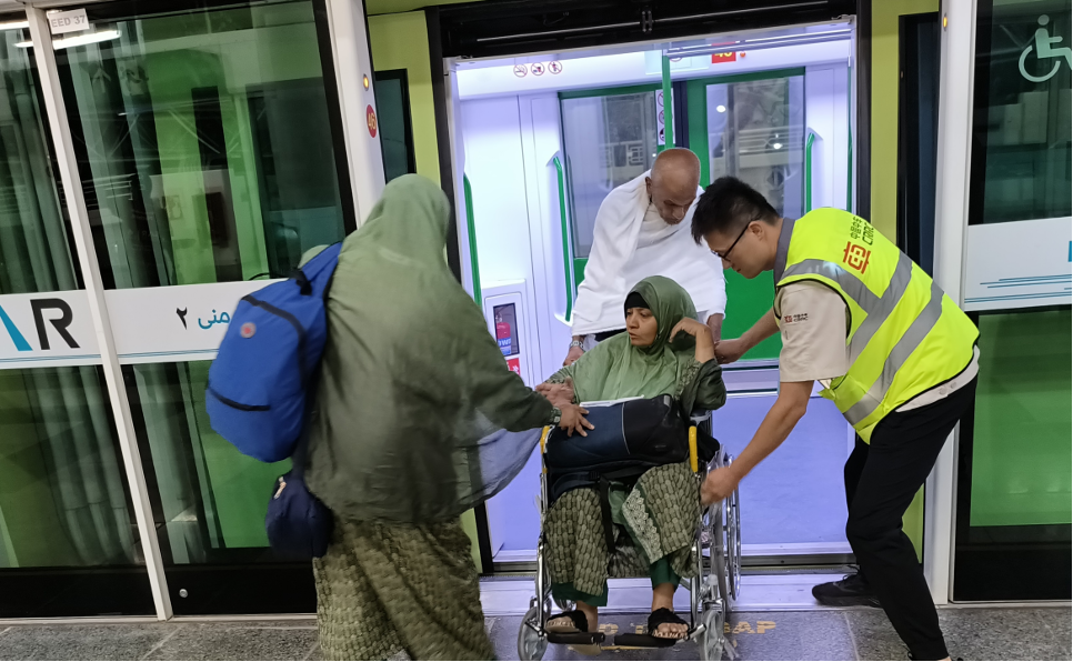 A CRRC staff member helps passengers disembark from the 