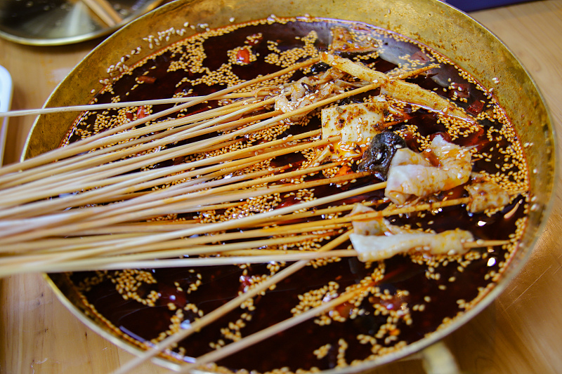 A photo shows one of the delicacies of Leshan City featuring vegetables and meat on bamboo skewers soaking in a cool spicy soup. /CFP