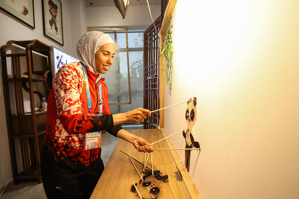 Photo taken on August 2, 2023 shows a foreign athlete experiencing China's intangible cultural heritage at the FISU Games Village in Chengdu, Sichuan Province. /CFP