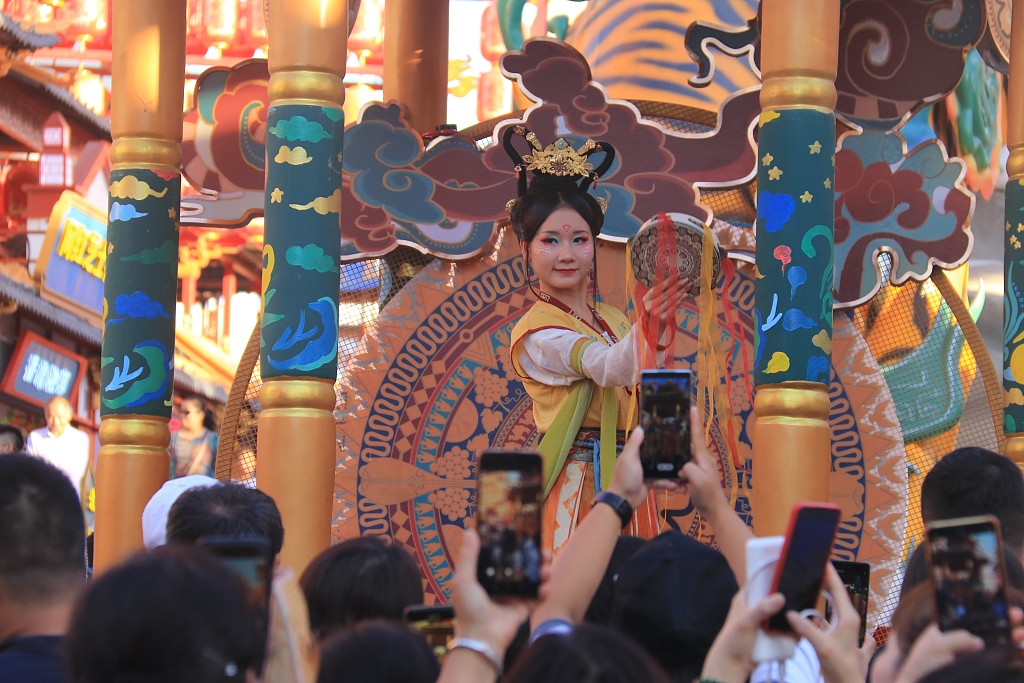 Photo taken on August 2, 2023 shows tourists enjoying a captivating ancient-style performance at Urumqi's late-night scenic spot Tianshan Bright Moon City. /CFP