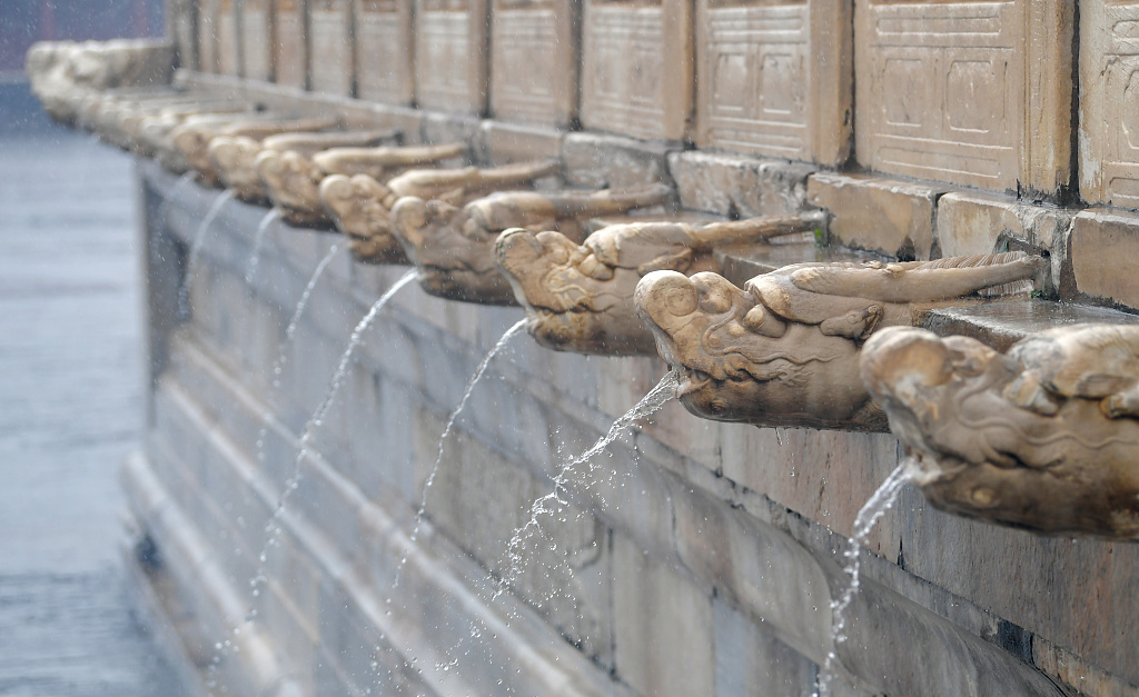 Photo taken on July 31, 2023 shows the dragon heads surrounding a high marble platform at the Palace Museum spouting water during heavy rains. The dragon heads serve as outlets to discharge ponding on the platform. /CFP