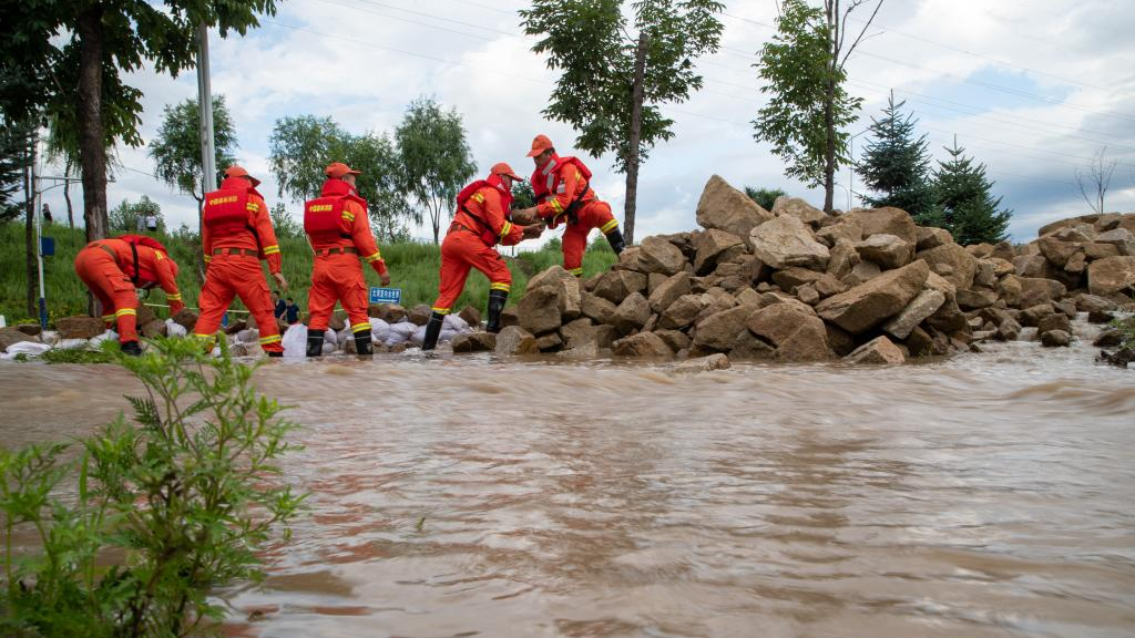 Firefighters transfer rocks to block floodwater near Dawan Village in Dong'an District, Mudanjiang, northeast China's Heilongjiang Province, August 5, 2023. /Xinhua