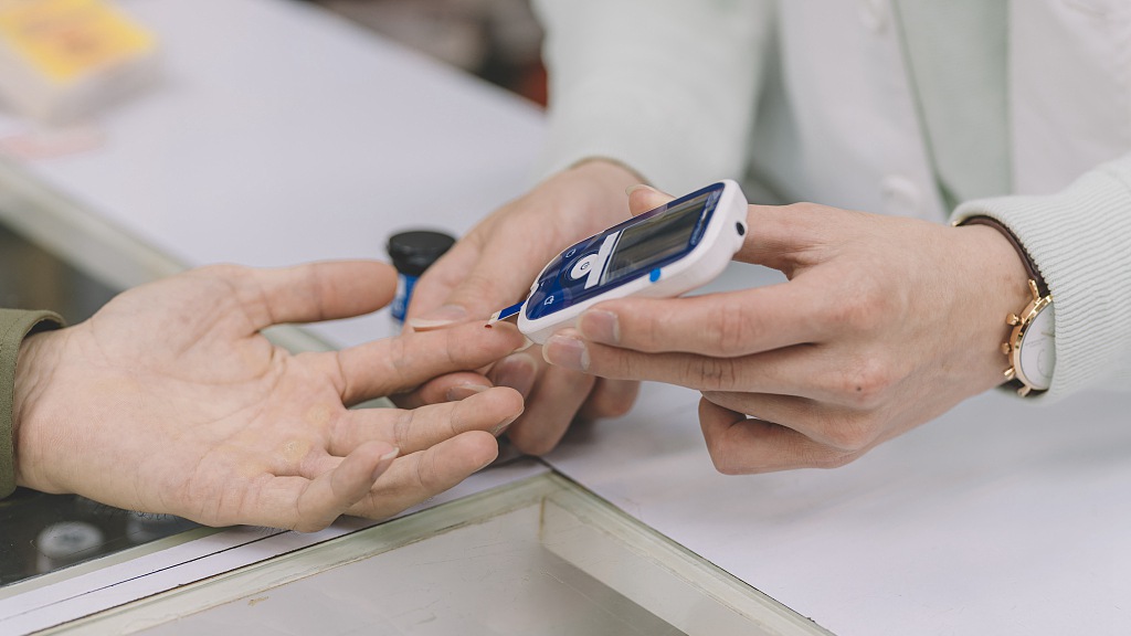 A physician helps a patient to test blood glucose. /CFP