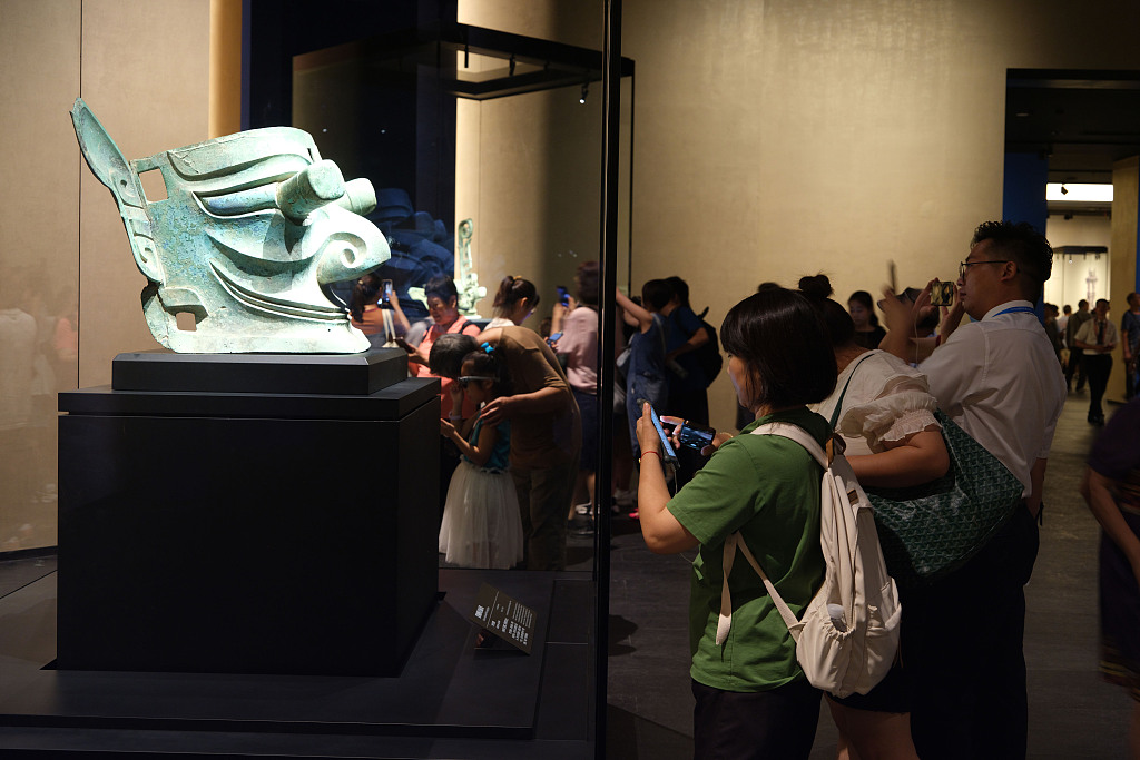 A photo taken on August 8, 2023 shows visitors viewing a replica of a giant bronze mask unearthed at the Sanxingdui Ruins believed to date back to the Shu Kingdom some 4,500 years ago. The exhibition took place at the recently-opened new venue of the Sanxingdui Museum. /CFP