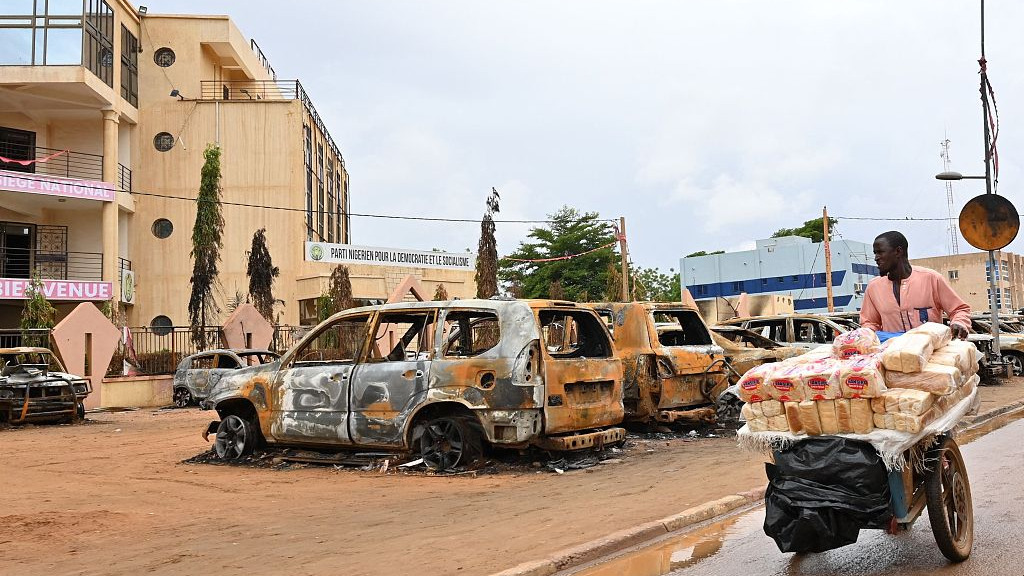 A street vendor pushes his cart past burned cars in Niamey, Niger, August 7, 2023. /CFP