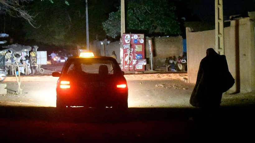 A woman walks past taxi during a black out affecting some districts of Niamey, Niger, August 4, 2023. /CFP