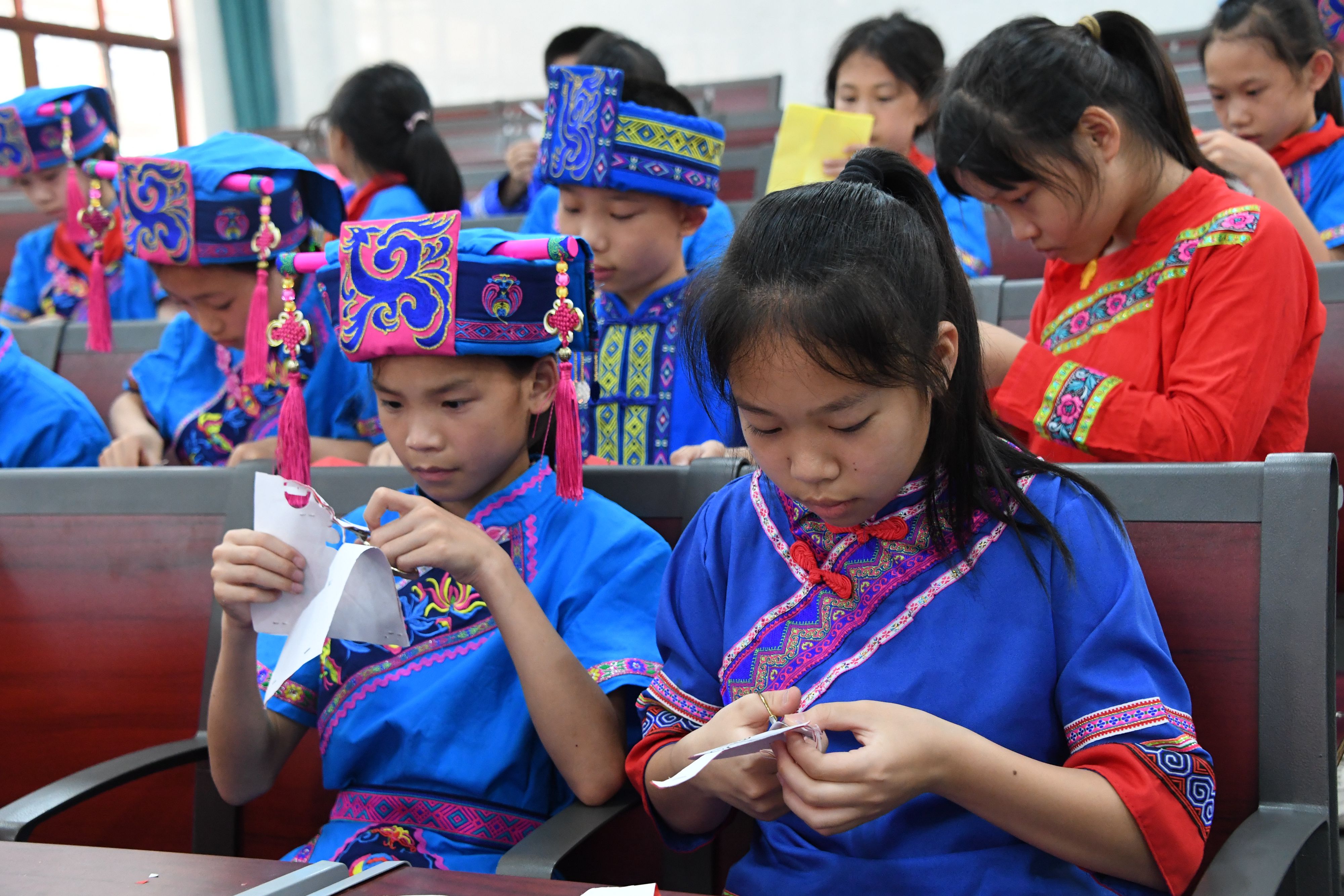 Students focus on creating Mulao papercuttings at a primary school in Hechi City, Guangxi Zhuang Autonomous Region, June 6, 2023. /CNSPHOTO