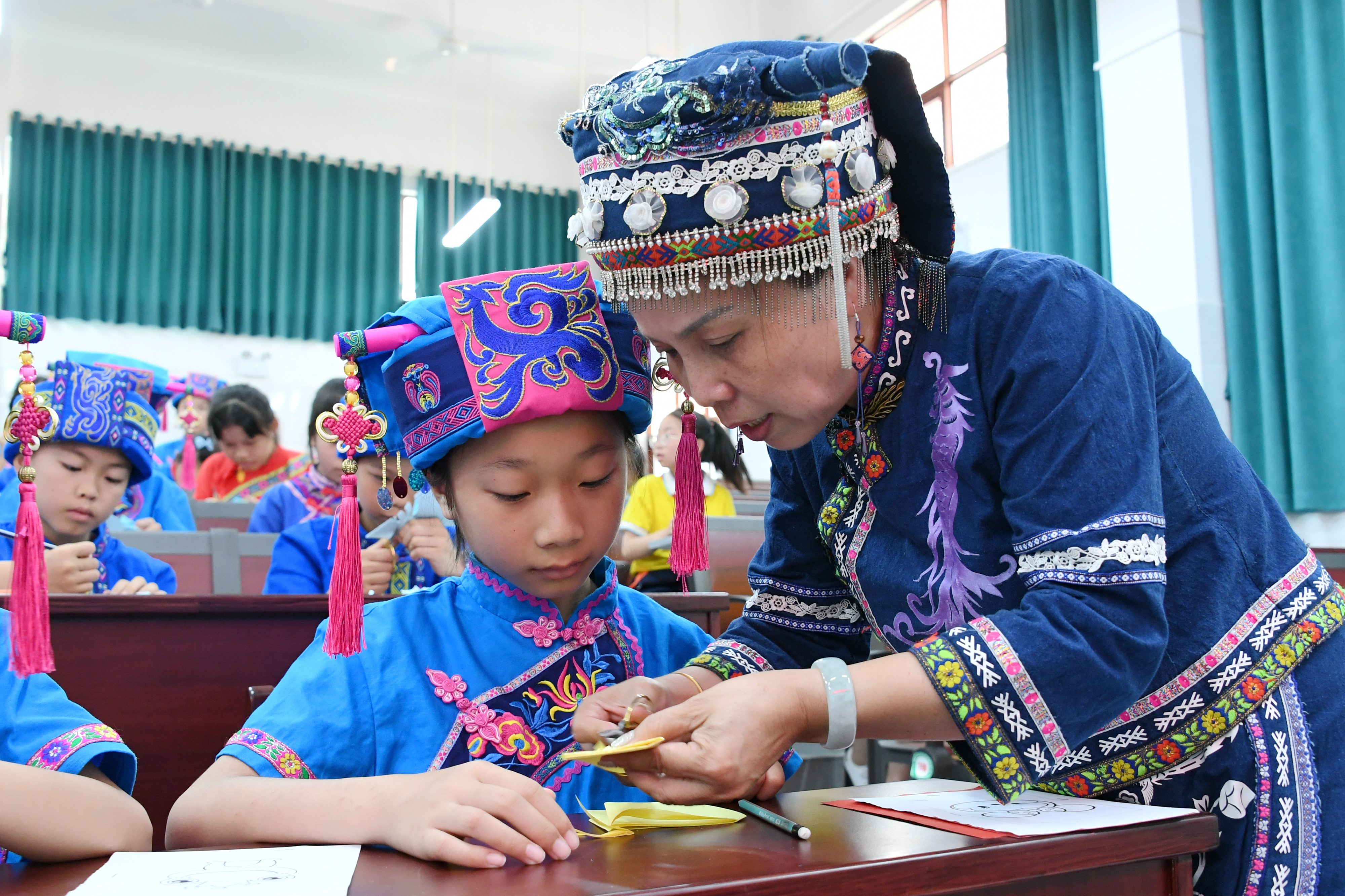 Students learn Mulao papercutting skills from their teacher at a primary school in Hechi City, Guangxi Zhuang Autonomous Region, June 6, 2023. /CNSPHOTO