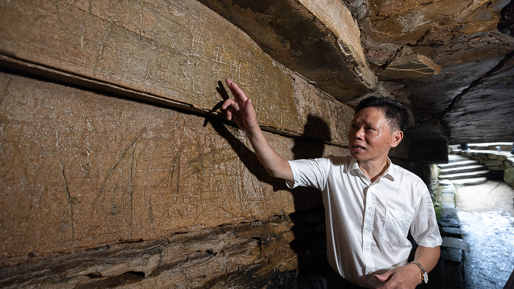A photo taken on August 9, 2023, shows an expert conducting research into the cliffside stone carvings discovered within a cave in the village of Huzhou, Zhejiang, China. /CFP