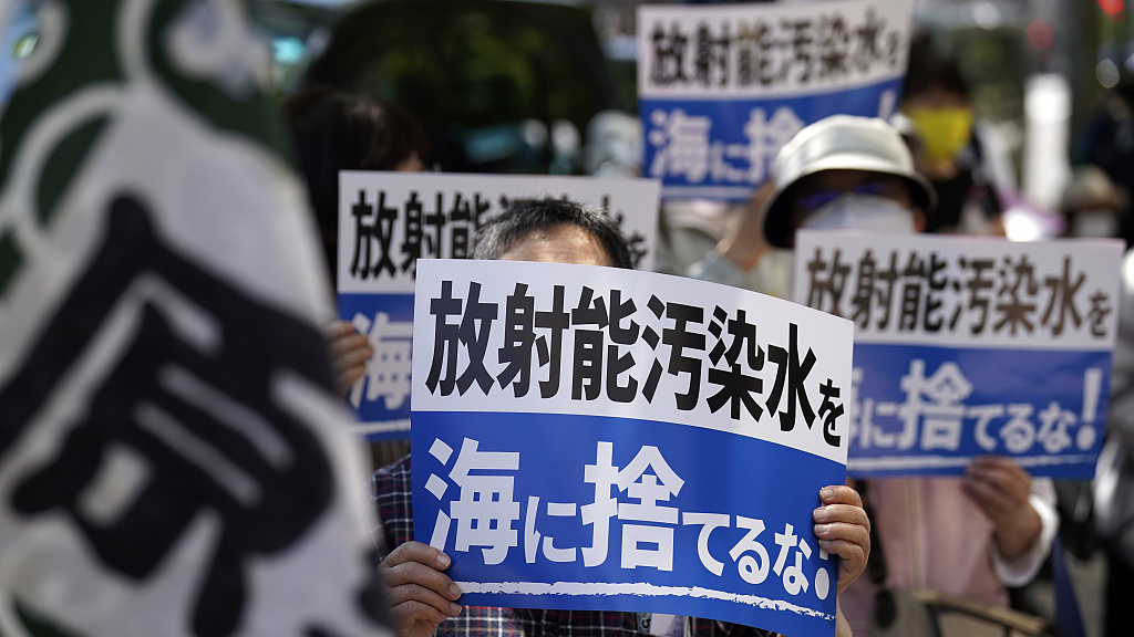 Protesters hold banners saying in Japanese 