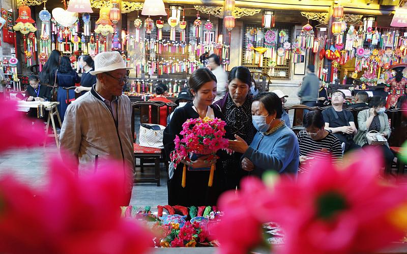 A local artisan explains how traditional sachets are made to visitors to the Ping'anyi and Hehuang Folk Culture Experience Block, Haidong City, Qinghai Province. /CFP