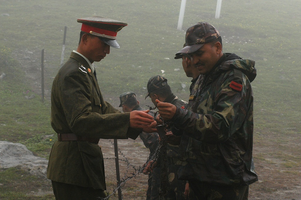 A Chinese soldier (left) and an Indian soldier try  to fasten the fence together at the Nathula Pass on the China-India border, July 5, 2006. /CFP
