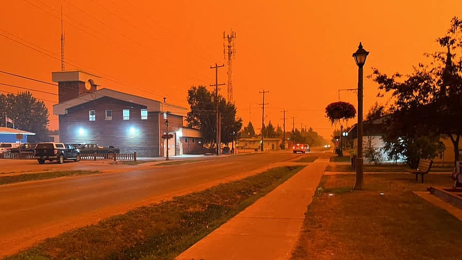 The town of Fort Smith in an orange haze as wildfires sweep Canada's far north, August 13, 2023. / AFP