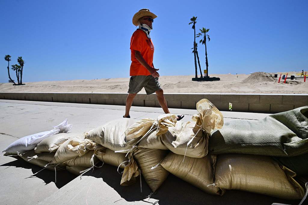 A man walks past sand bags placed to protect beachfront homes in Seal Beach, California, U.S., August 18, 2023. /CFP