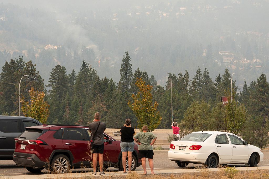 People park at a viewpoint to check on their homes as flames erupt during the McDougall Creek wildfire in West Kelowna, British Columbia, Canada, August 19, 2023. /CFP