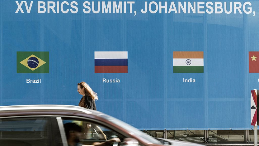 A lady walks past a poster for the 2023 BRICS Summit at the Sandton Convention Center in Sandton, South Africa, August 20, 2023. /CFP