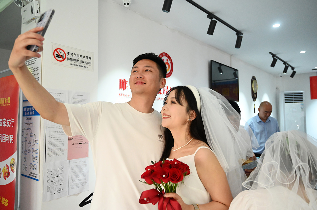 A photo, taken on August 22, 2023, shows a newly registered couple taking selfies at the local municipal civil affairs bureau in Xuzhou, Jiangsu Province, China. /CFP