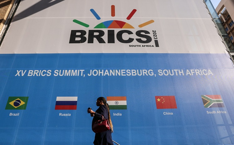 A lady walks past a banner advertising the 2023 BRIC summit at the Sandton Convention Center in Johannesburg, South Africa, August 20, 2023. /CFP