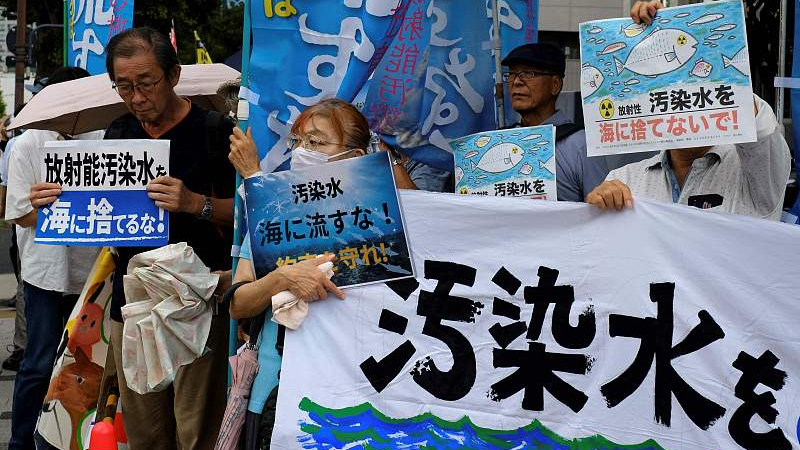 Protesters hold signs as they take part in a rally against the Japanese government's plan to release nuclear-contaminated water, Tokyo, August 22, 2023. /CFP
