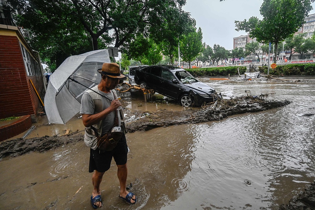 A man stands in the rain as Mentougou District is flooded by heavy rain, Beijing, August 1, 2023. /CFP