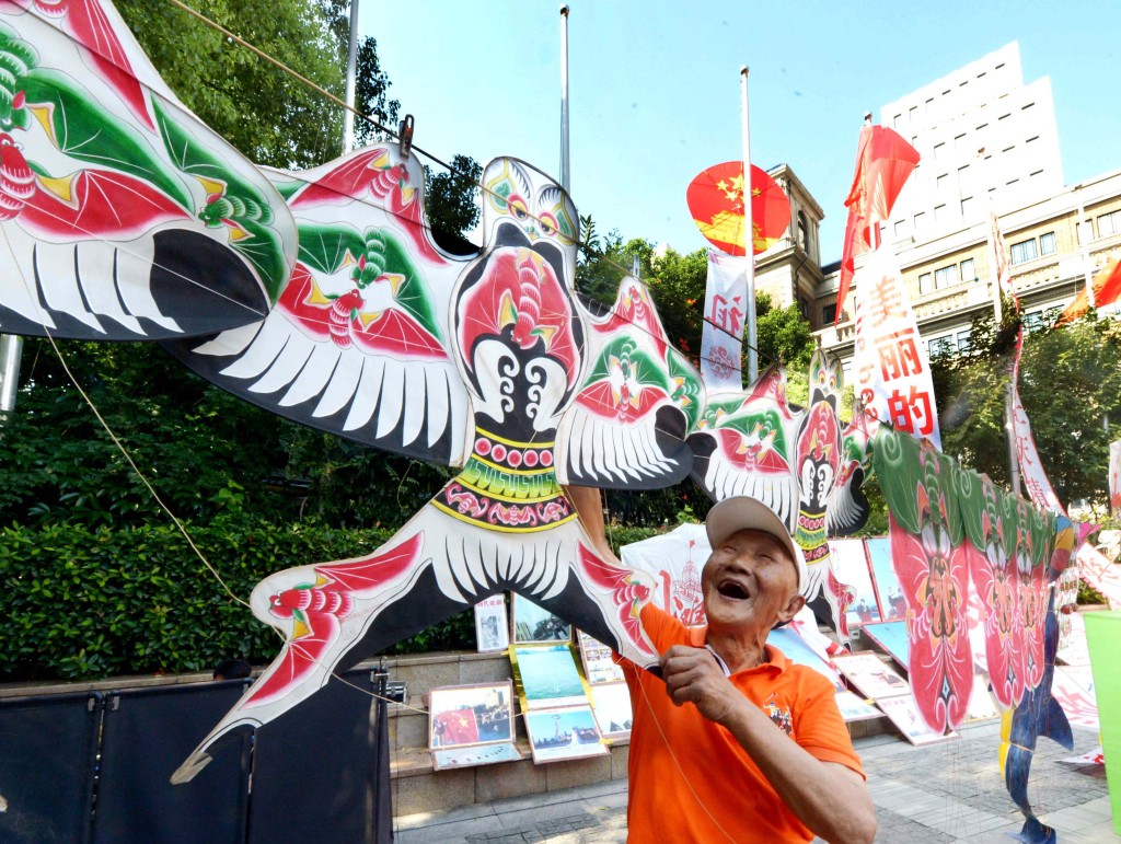 A man shows his kite during a kite exhibition held on August 24, 2023 at The Bund in Shanghai. /CFP