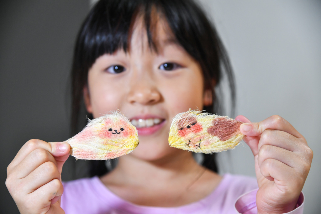 A pupil from a Beijing elementary school shows her mango pit-made pet dogs. /CFP