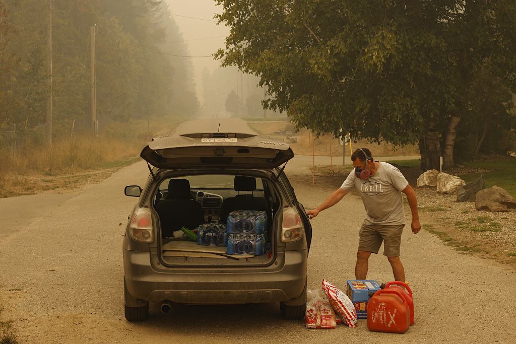 A resident collects supplies after a supply drop during a wildfire in the evacuated town of Scotch Creek, British Columbia, Canada, August 20, 2023. /CFP