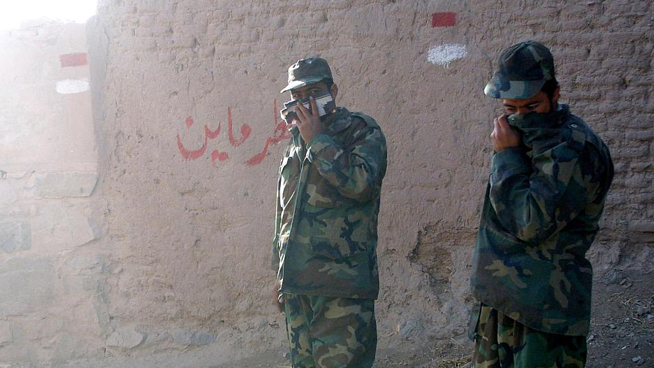 Afghan members of a local organization for mine clearance cover their faces as they detonate U.S. cluster bombs in Herat City, Afghanistan, November 22, 2001. /CFP 
