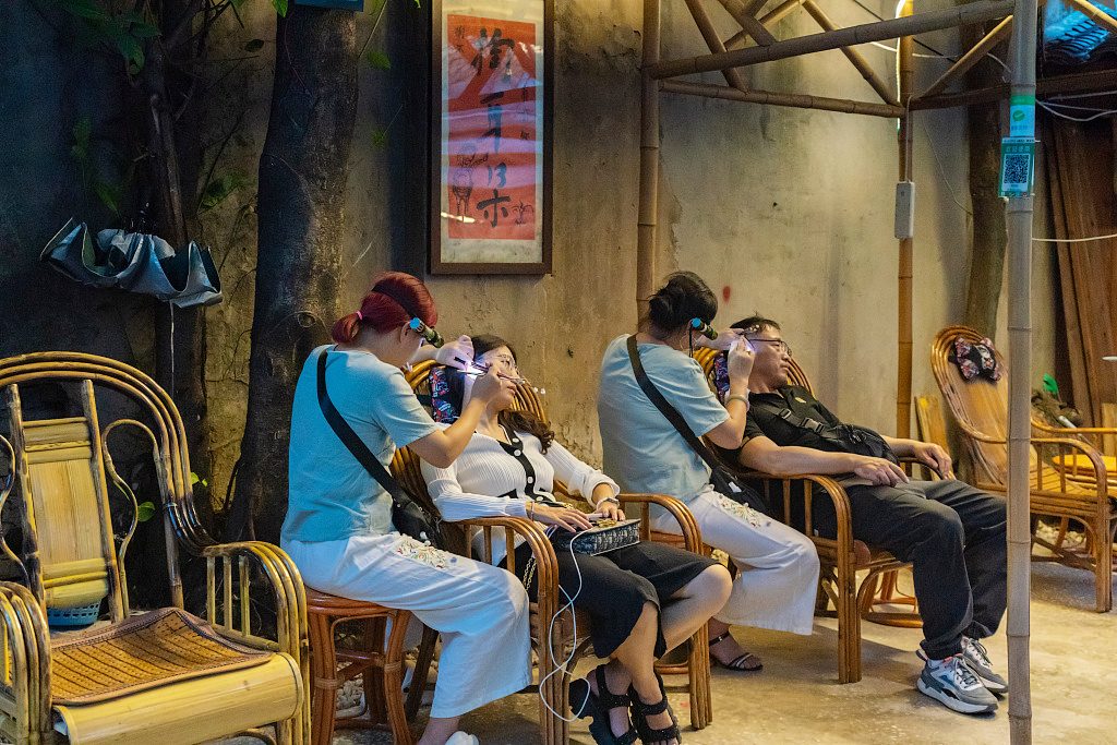 Visitors enjoy an ear-cleaning service at Shancheng Alley in Chongqing on August 30, 2023. /CFP